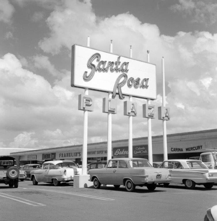 A 1970's photograph of a Santa Rosa Plaza neon sign above the parking lot.